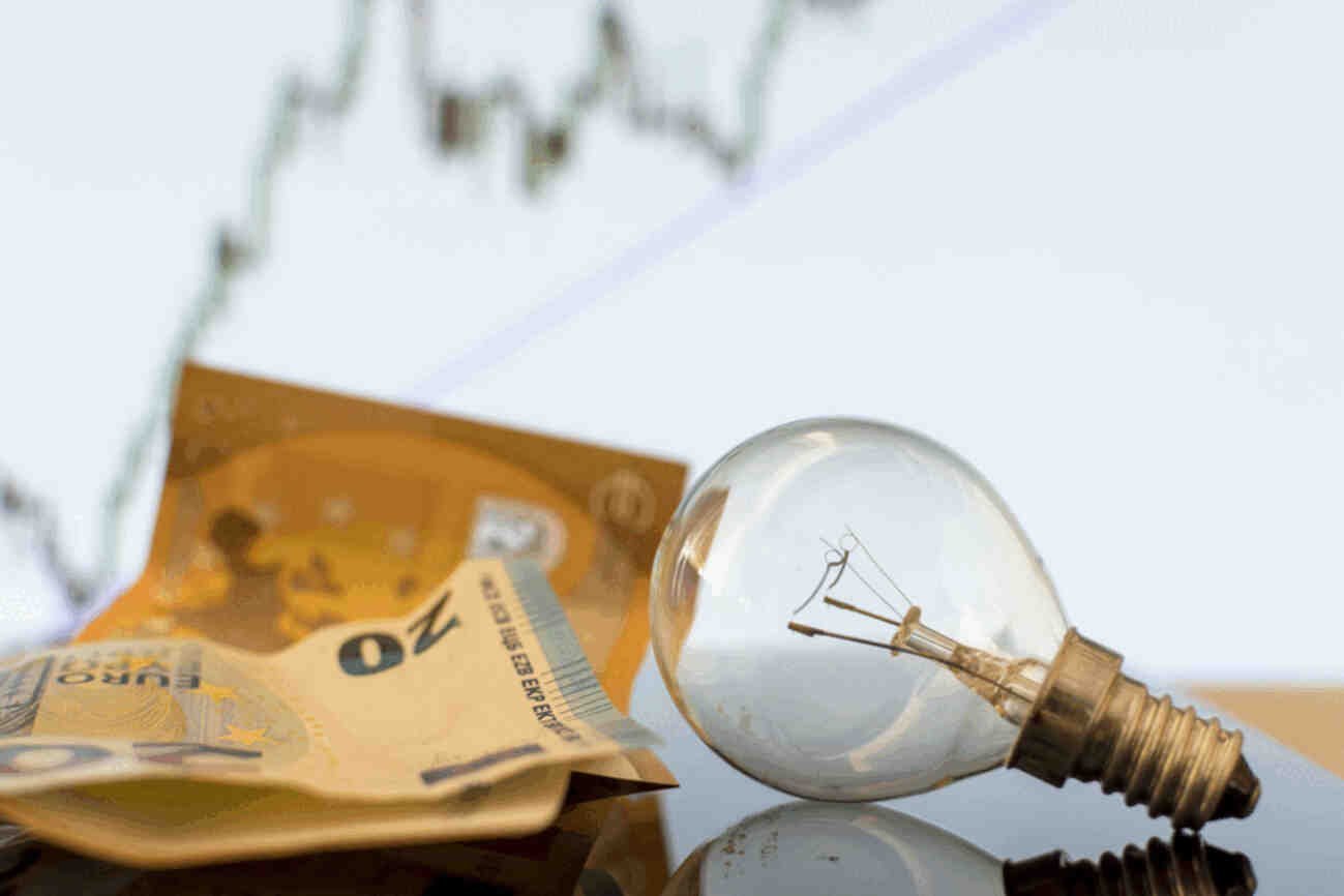bombilla incandescente junto a billetes de euro, representando el costo de la electricidad